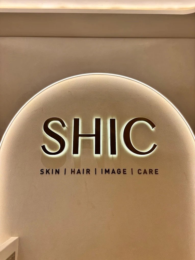 The backlit SHIC sign on the clinic's reception wall: Skin, Hair, Image, Care